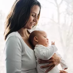 Woman holding her baby in front of her while smiling