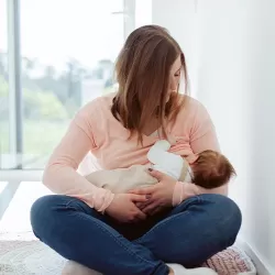 Woman breastfeeding her baby while sitting with legs crossed